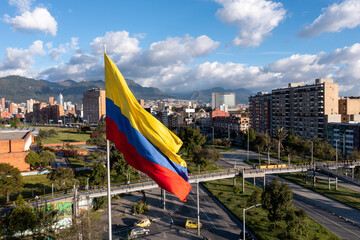 Photo of the Colombian flag on a pole with avenue and city buildings in the background. Bogotá....
