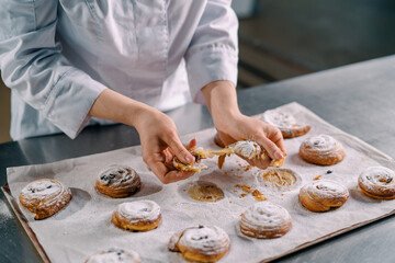 beautiful woman baker tears ready freshly baked hot aromatic buns and checks dough bakery production