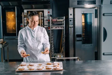 Foto op Plexiglas beautiful woman baker tears ready freshly baked hot aromatic buns and checks dough bakery production © Guys Who Shoot