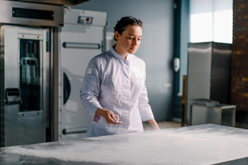 professional chef throws flour on table making flour clouds before preparing bread pastry in bakery in professional kitchen