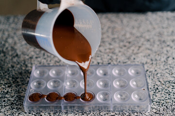 Pouring chocolate into molds in a professional kitchen tempering chocolate making candies