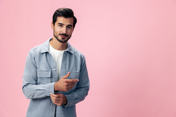 Portrait of a stylish brunette man with a beard beautiful smile on a pink background in a white T-shirt and jeans smile and joyful emotion on his face, copy space