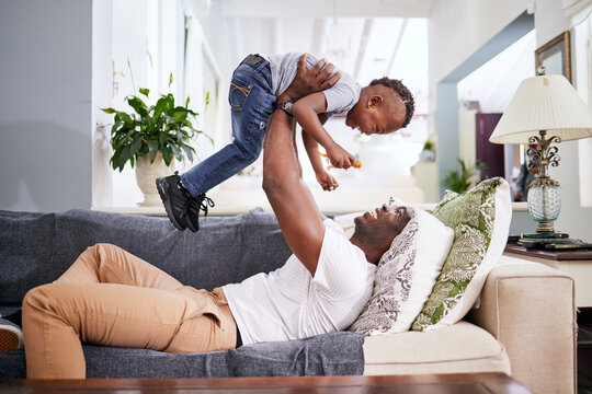Black family, airplane and father with son on a sofa with love, lifting and playing in their home together. Flying, child and fun with parent on sofa, laugh and play, bonding and games in living room