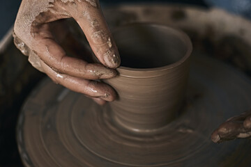 Hands of craftsman artist working on pottery wheel.