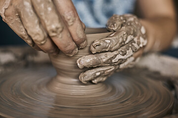 Hands of craftsman artist working on pottery wheel.