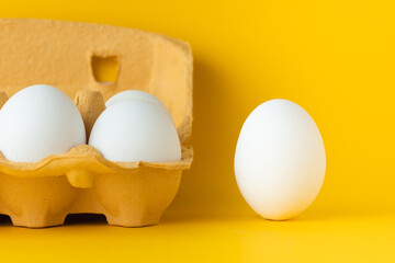 Close up shot of white eggs in the carton brown box on the yellow background. Macro shot. Copy...