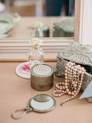 Women's dressing table in vintage style. Vintage jewelry box with pearl beads, hand mirror, perfume, powder.