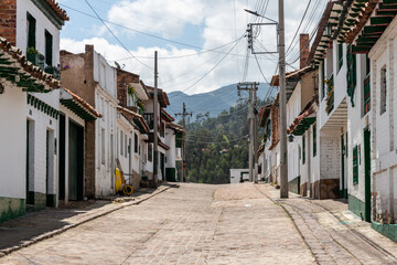 Fototapeta na wymiar Typical street, with white colonial spanish facades, of the beautiful historical Colombian village Mongui ((Monguí), Boyaca, Colombia.