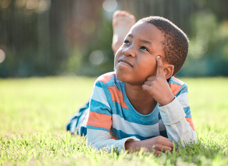 Nature park, black boy thinking and lying on grass outside at park with a lens flare. Day dreaming...