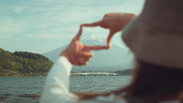 Back view of young traveler girl making frame gesture by hands with mount fuji in japan, spring and summer, Planning Japan travel vacation.