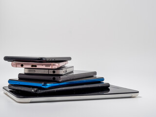 Damaged mobile phones. A bunch of broken smartphones. Used phones on a light background.