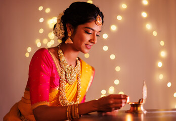 Obraz na płótnie Canvas Beautiful Hindu Indian young women lightening deepa on Diwali day.
