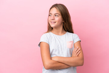 Little caucasian girl isolated on pink background with arms crossed and happy