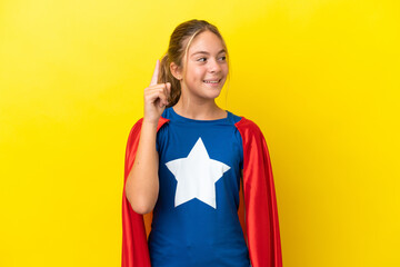 Super Hero little girl isolated on yellow background intending to realizes the solution while lifting a finger up