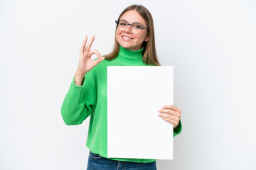 Naklejka premium Young caucasian woman isolated on white background holding an empty placard and doing OK sign