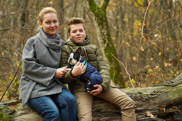 Happy family with a dog in the woods. Mom and son on a walk with a pet.