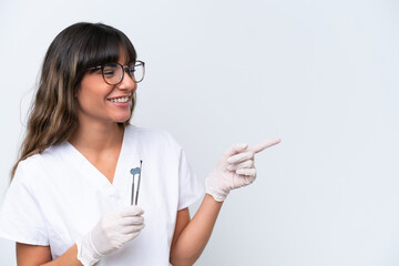 Dentist caucasian woman holding tools isolated on white background pointing finger to the side and presenting a product