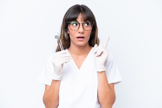 Dentist caucasian woman holding tools isolated on white background thinking an idea pointing the finger up