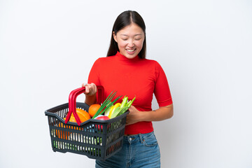 Obraz na płótnie Canvas Young Asian woman holding a shopping basket full of food isolated on white background smiling a lot
