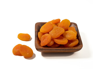 Wooden bowl of dried apricots on a white background, selective focus. Dried apricots close up.