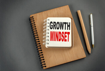 GROWTH MINDSET text on notebook with pen and pencil on grey background