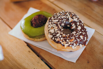 two sweet donuts on a white plate, chocolate peanut and green tea