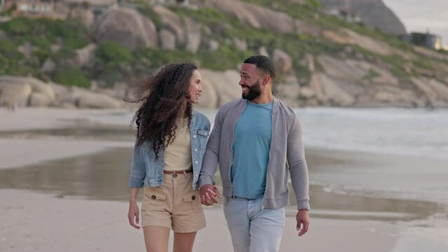 Happy couple, walking and holding hands on the beach for travel, holiday or weekend together in nature. Man and woman on sunset walk with smile in happiness for bonding relationship on ocean coast