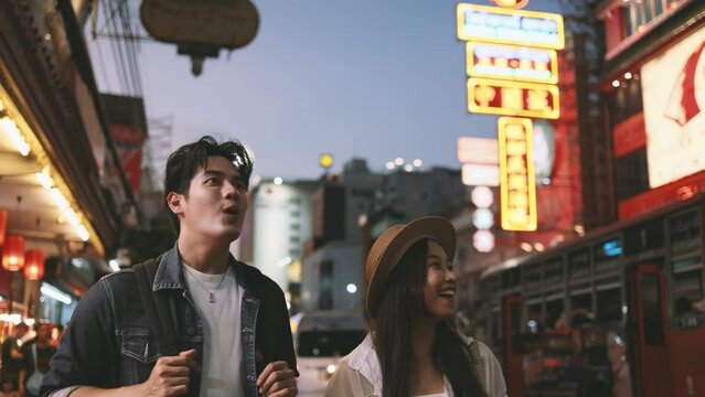 Young Asian couple enjoy and have fun outdoor lifestyle together in street market on summer holiday vacation in bangkok, thailand. Happy man and woman feeling surprise about how beautiful the city is