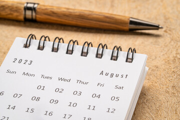 August 2023 - closeup of a small desktop calendar with a pen, time and business concept