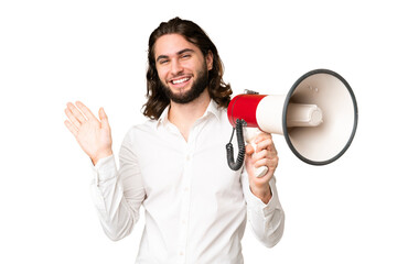 Young handsome man over isolated chroma key background holding a megaphone and saluting with hand...