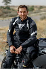 Fototapeta na wymiar Guy biker in leather jacket looking at the camera sitting on motorcycle. Selective focus