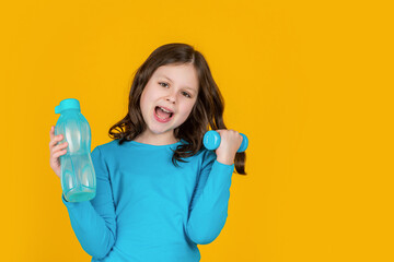 happy child with barbell and sport bottle on yellow background