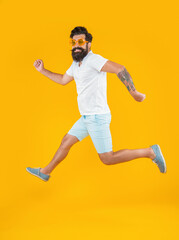 Fototapeta na wymiar running caucasian stylish guy in studio isolated on yellow background