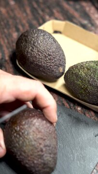 One person cut in half a ripe avocado