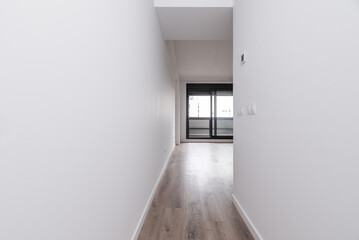 Hallway of a house with white walls and wooden floors