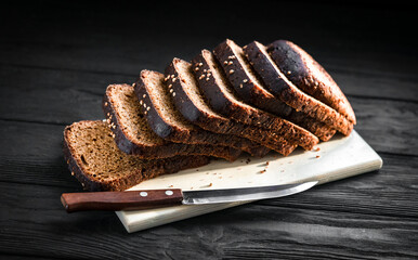 black bread on a wooden board on a black background