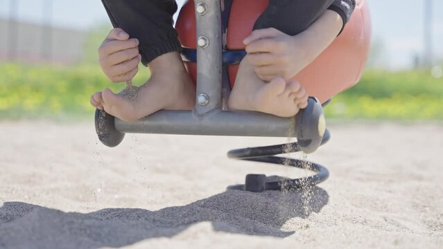 Unrecognizable child grabs a handful of dry sand and lets it fall on feet