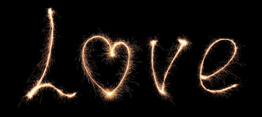 The word love consists of sparklers on a dark background, golden letters with a heart in the middle...
