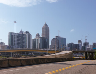 Downtown Atlanta Skyline showing several prominent buildings, high rises, cranes, highway and hotels under a blue sky.