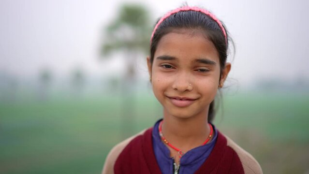Happy Indian girl looking at camera and smiling in outdoor setting, Indian countryside. 
