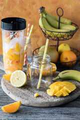 An empty jar mug with a straw awaiting a blended mango citrus smoothie