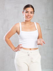 Fototapeta na wymiar Young positive woman in casual clothes posing against studio background
