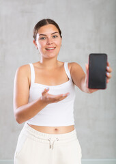 Smiling young girl showing modern smartphone with blank screen