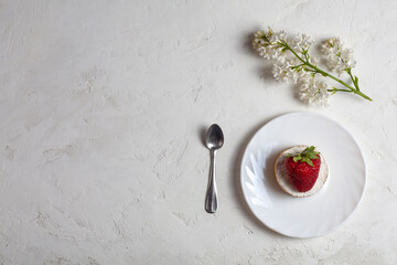 On the table are strawberry cookies, a teaspoon and a white flower. On a white background. Copy space.