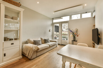 a living room with wood flooring and white furniture in the center of the room is a large window that looks out onto the