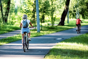 A young woman riding a bicycle in a park in summer in the sunny morning.