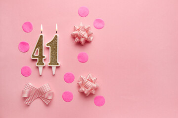 Number 41 on pastel pink background with festive decor. Happy birthday candles. The concept of celebrating a birthday, anniversary, important date, holiday. Copy space. Banner