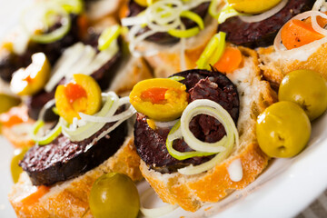 Fototapeta na wymiar Appetizing sandwiches with slice of blood sausage and green olives stuffed with carrots..
