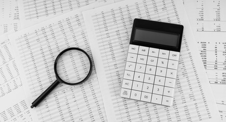 Calculator and magnifying glass on financial statement. Financial, accounting and business concept.