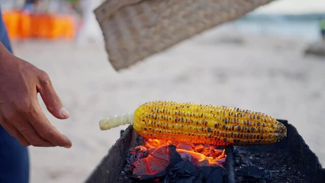Man's hands hold a cob of corn over the fire, Close-up, Slow motion